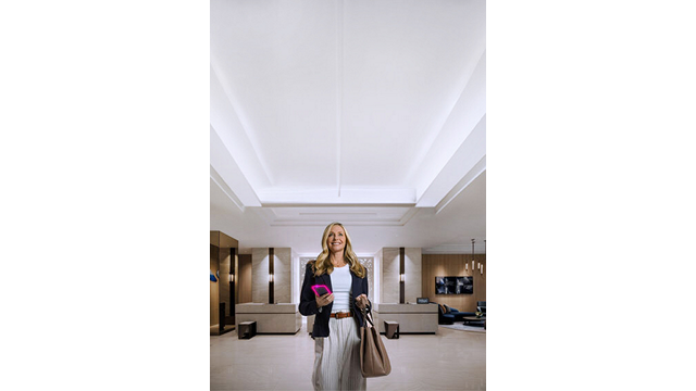 A woman stands in the lobby of a Hilton hotel with a bag in her hand.