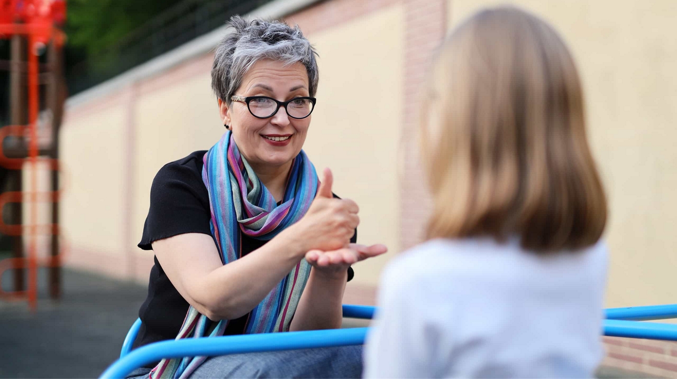 An educator signing to a student outside.