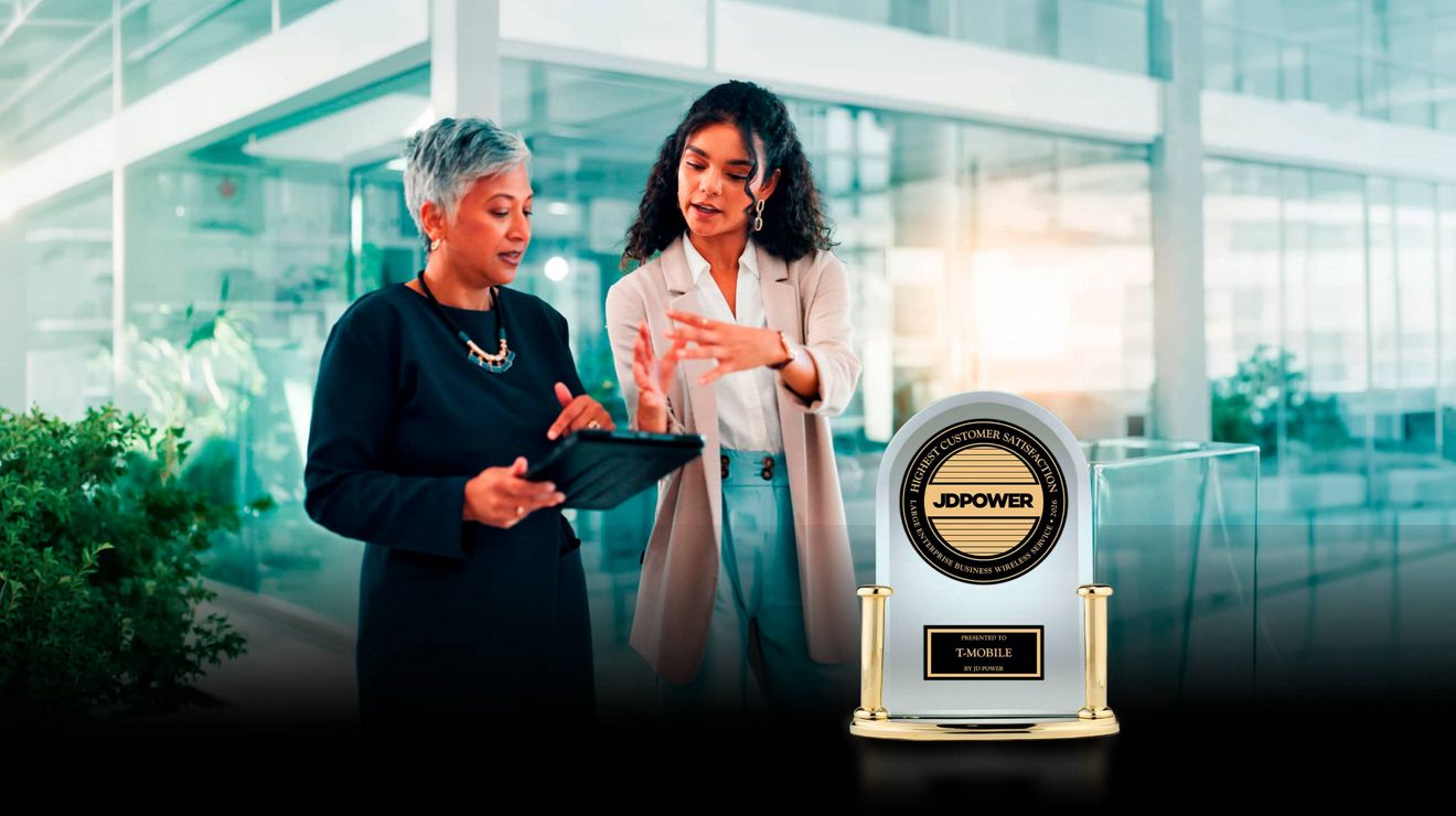 Two managers use a connected tablet while walking through an office, behind a JD Power award for business wireless customer satisfaction.