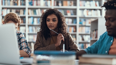 Group of people in a library looking at a laptop