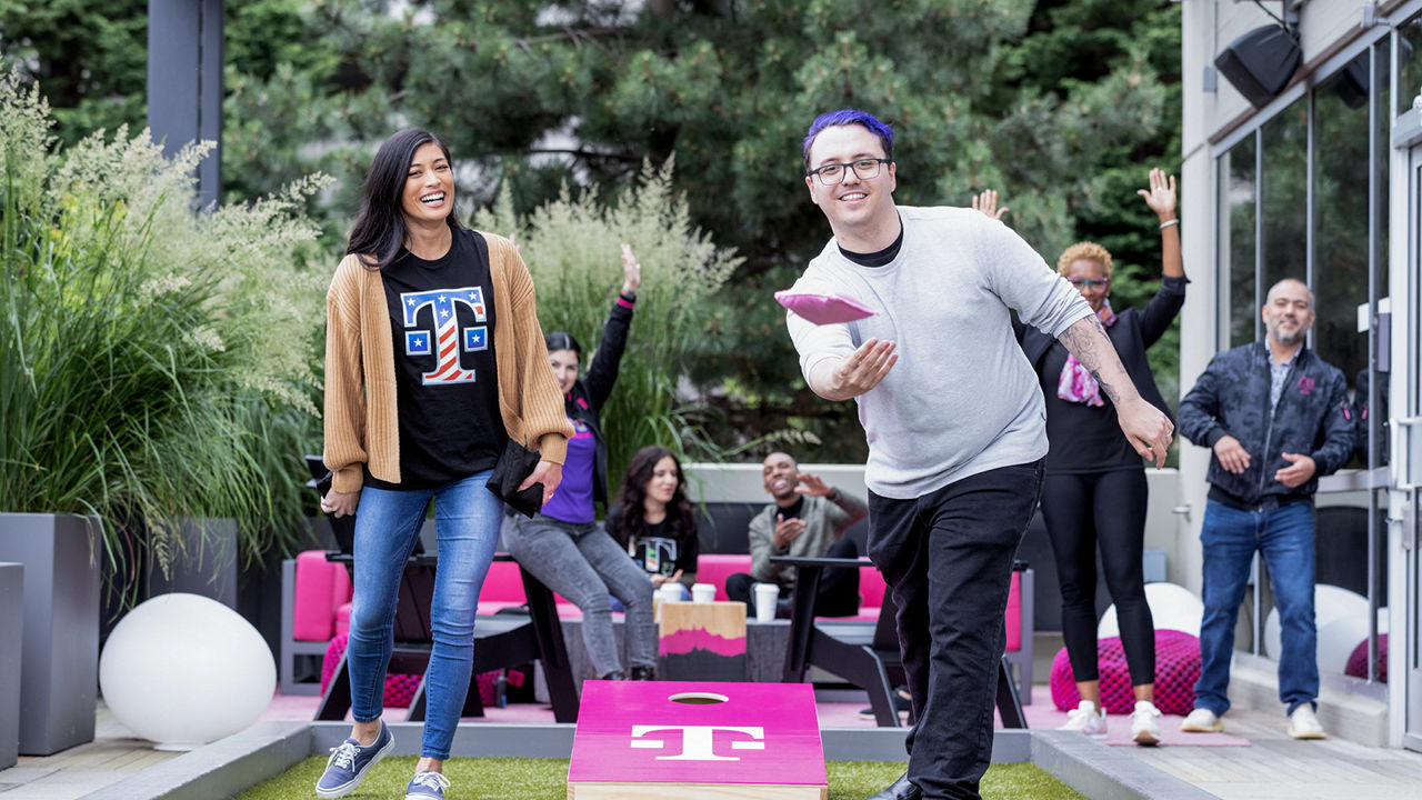 Two T-Mobile employees playing cornhole outside
