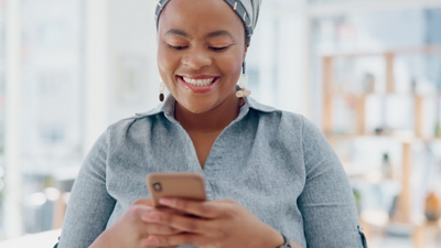 Head-on picture of smiling person texting on their smart phone