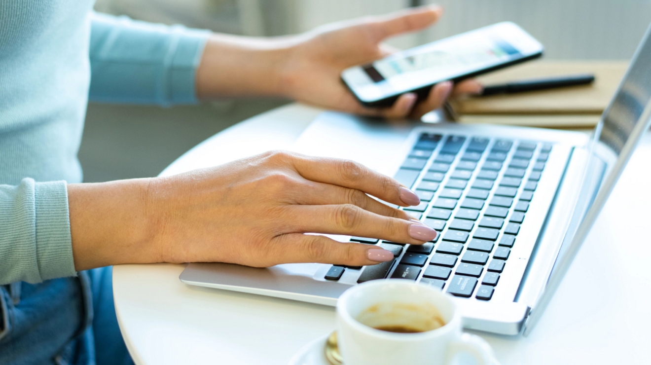 Close up of laptop keyboard and a device in the background