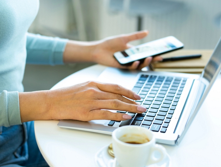 Person working on a smartphone and a laptop