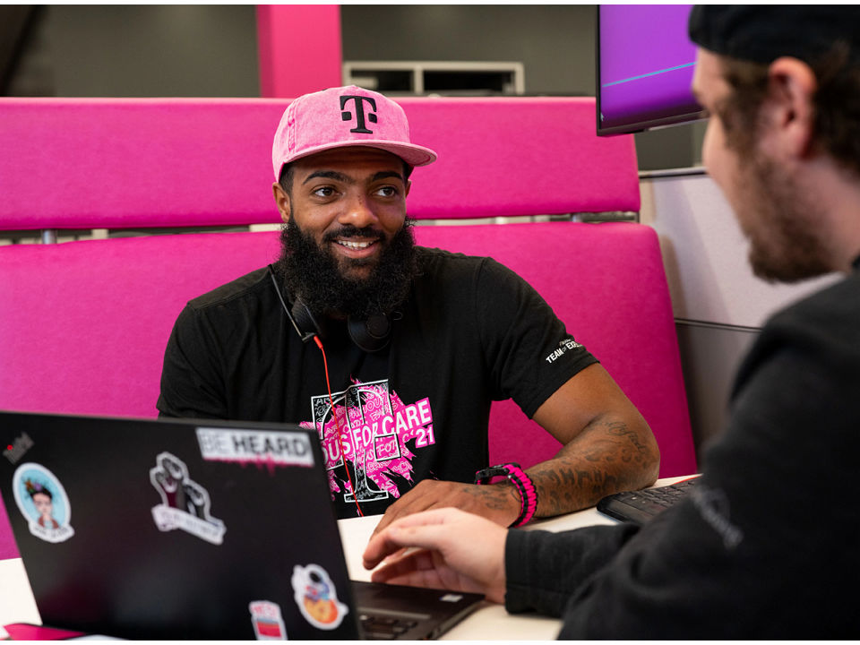 T-Mobile employee in a magenta hat, smiling at a customer.
