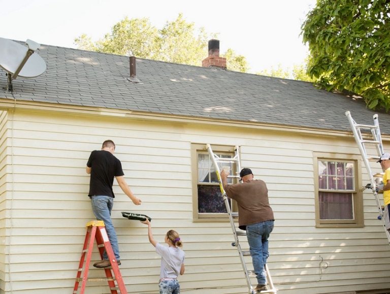 Volunteers on ladders painting a house