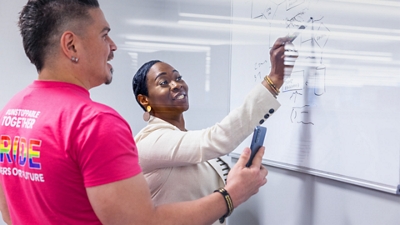 Two T-Mobile employees working together in an office on a dry erase board