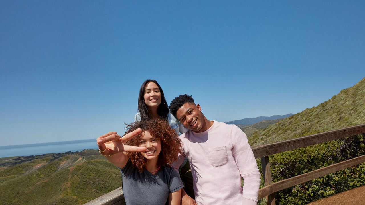 Group of three people posing for photo on a mountain