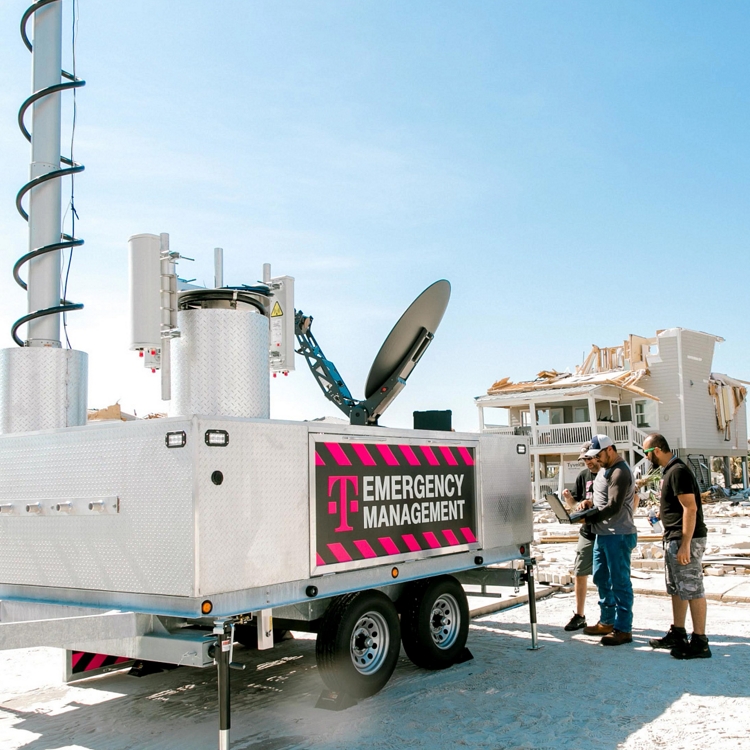 T-Mobile team gathered around a laptop beside T-Mobile Emergency Management equipment