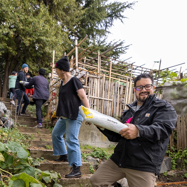 Crew of people forming a chain up a set of outdoor stairs and handing bags to each other