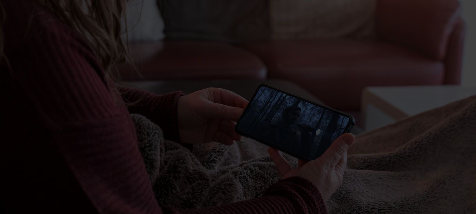 Someone under a blanket, watching a movie on their 5G phone 