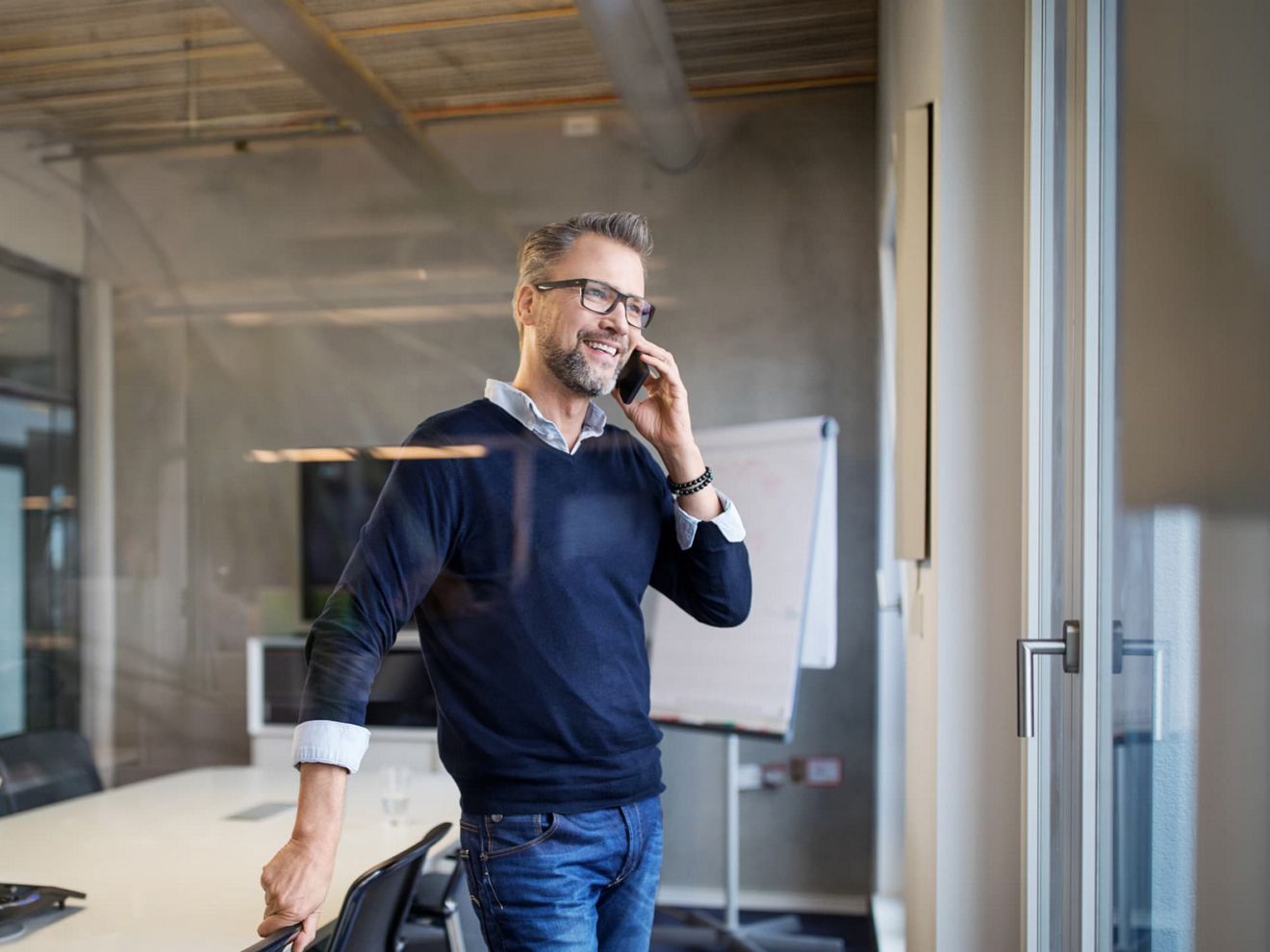 A business pro in an empty conference room connects on his smartphone using T-Mobile MultiLine.