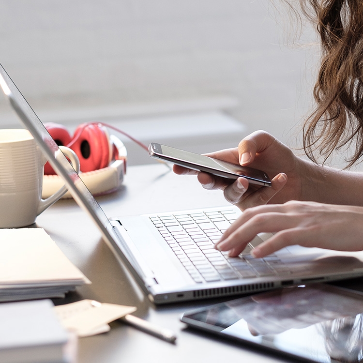 A woman on the computer and using her phone.
