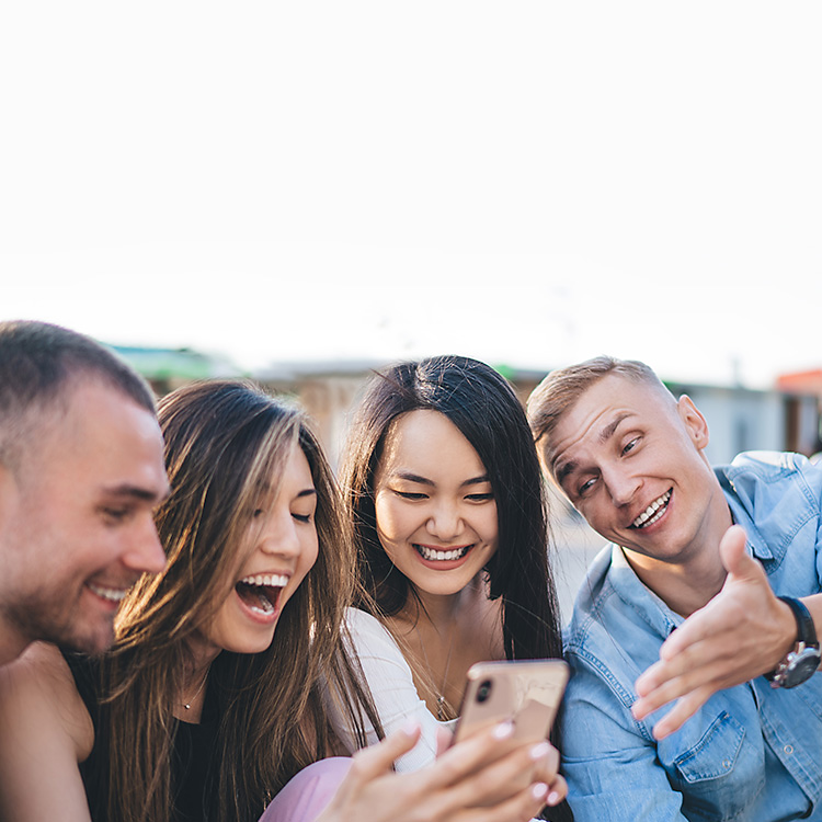 Four friends looking at an iphone and smiling