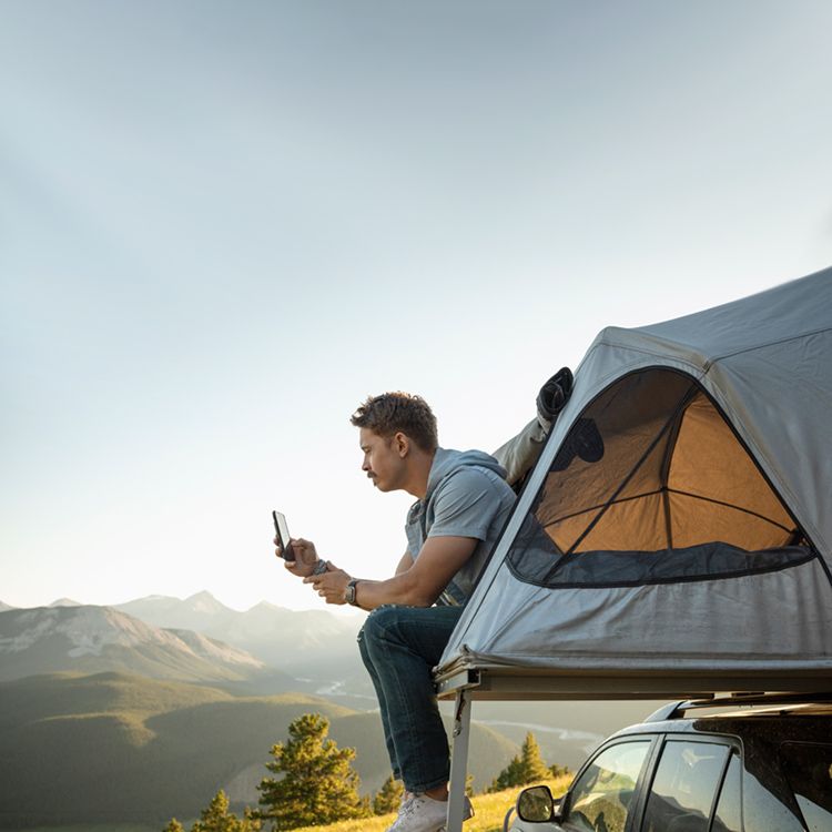 Man looking at smartphone to check Sync up Drive app while in a tent.