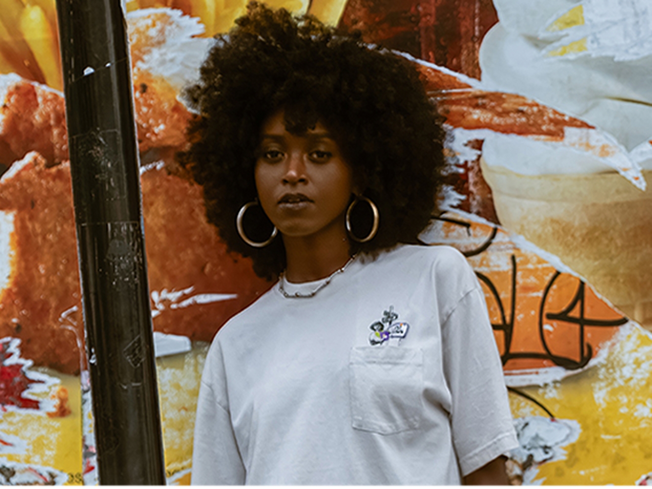 A woman wears the exclusive T-shirt from The Price Drop Drop featured artist Mía Lee,  