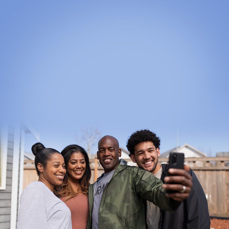 Group of four smiling and taking a selfie.