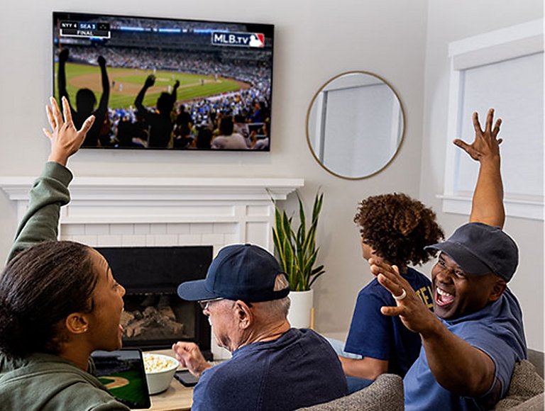 A group of friends on a couch cheer for an MLB game on the television.