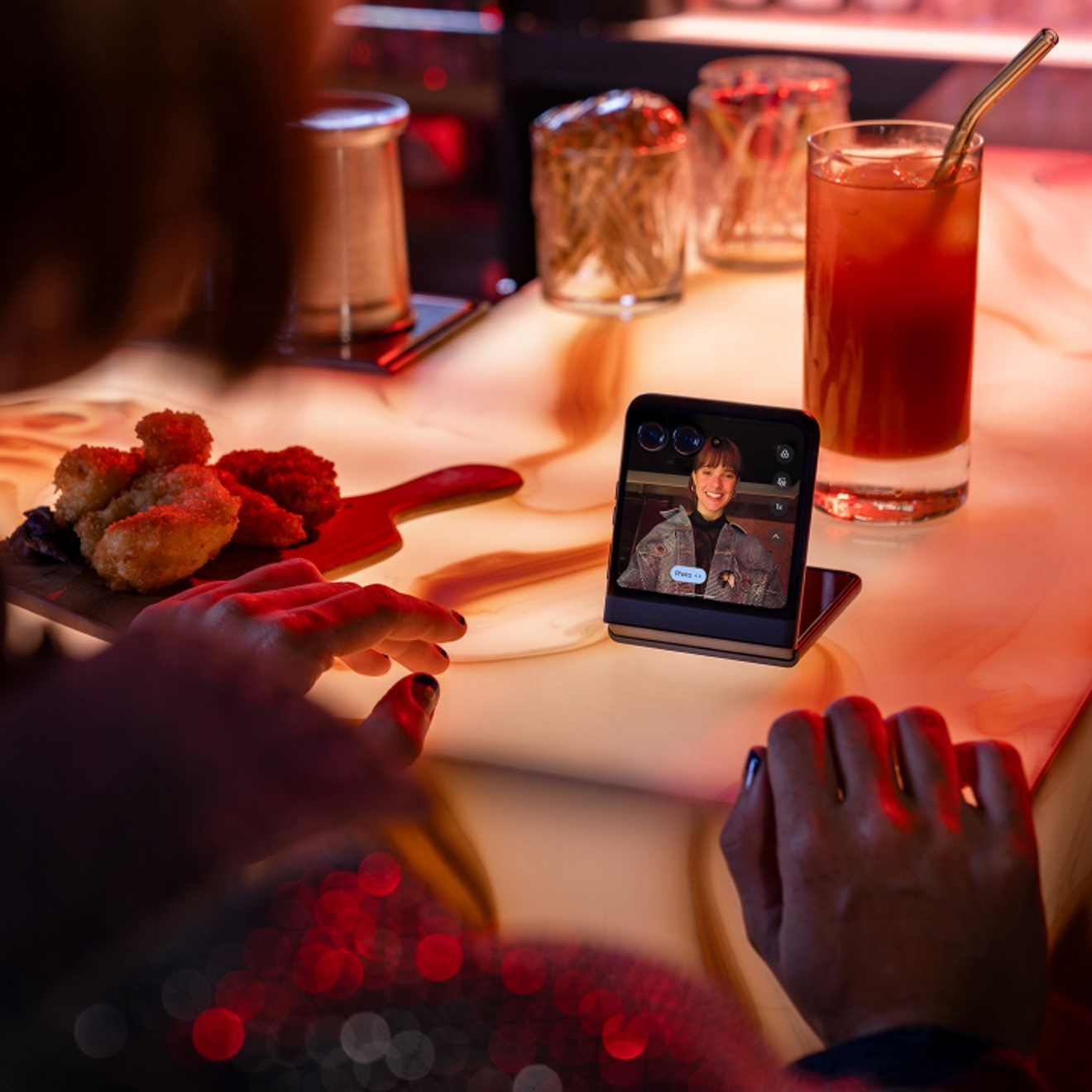 Person at restaurant using Motorola razr to video chat with friend.