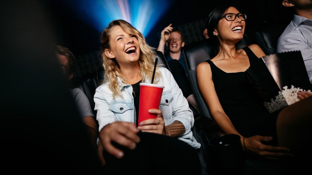 Moviegoers enjoy a comedy in a dark theater.