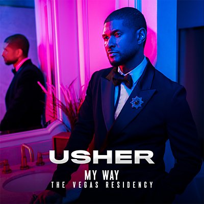 Usher stands in front of a mirror, shaded in blue and pink lighting.
