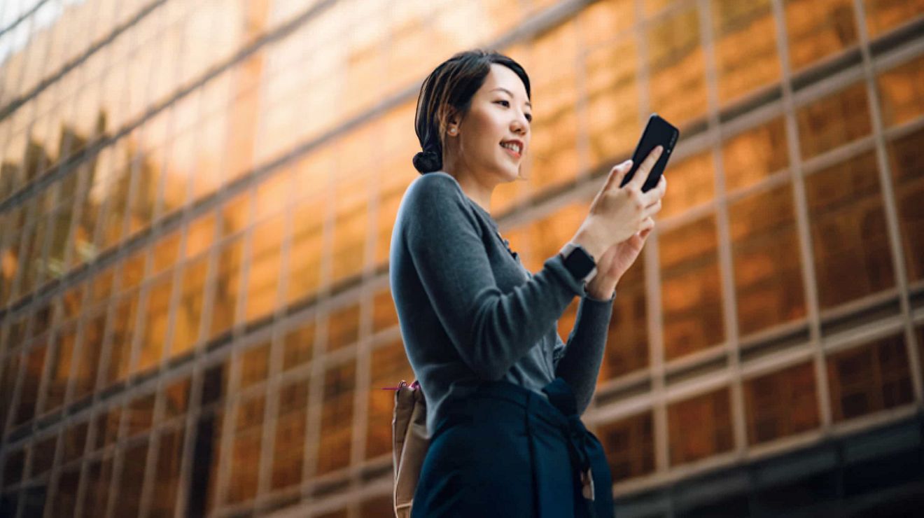 A businessperson on a city street texts a colleague via their T-Mobile 5G connected smartphone.