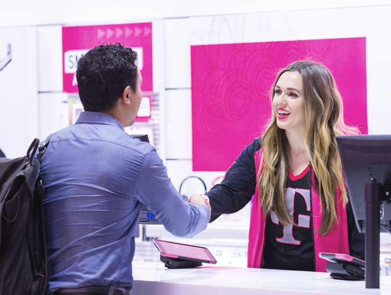 A T-Mobile employee shaking hands with a customer in a T-Mobile retail store