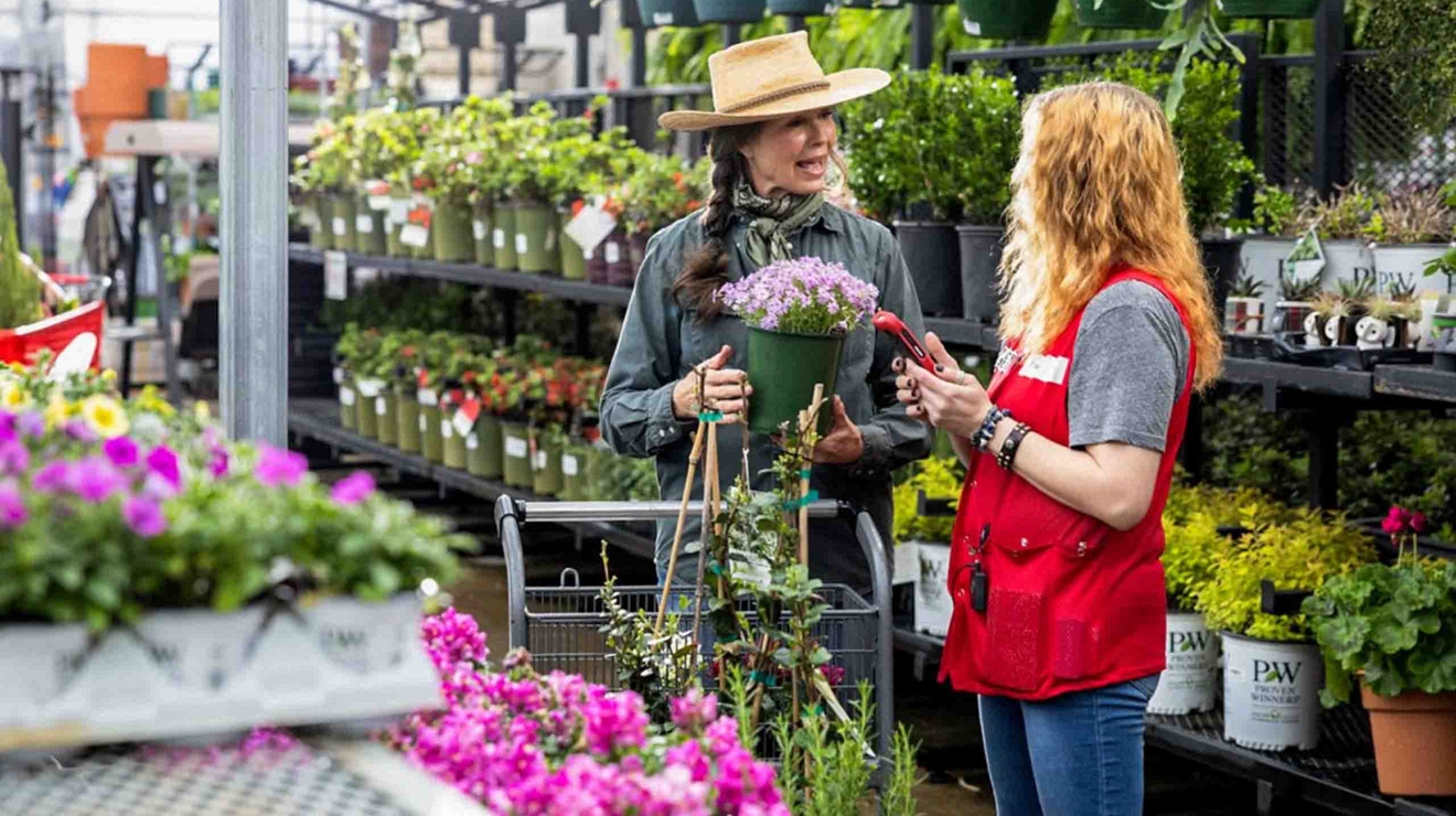 A retail plant nursery employee uses her smartphone to help a customer check pricing and availability.