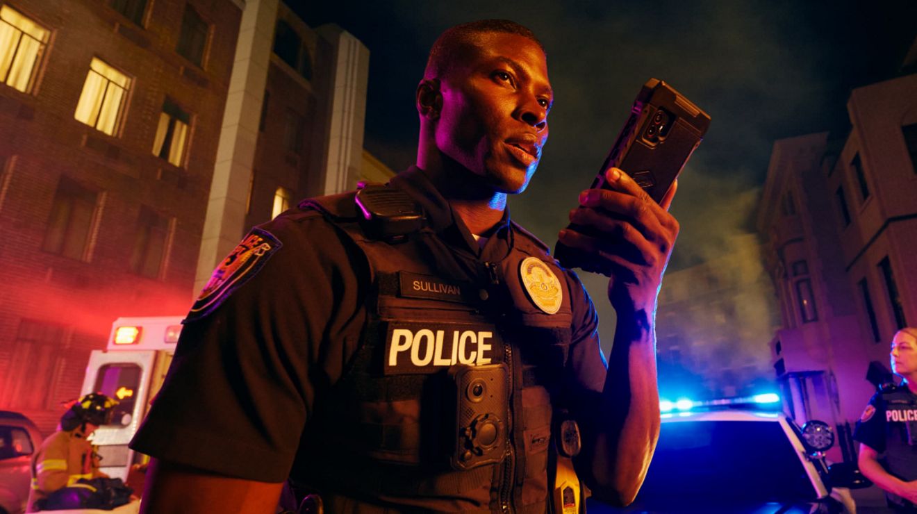 A police officer at the scene of an emergency uses the 5G network to send critical data from a digital device.