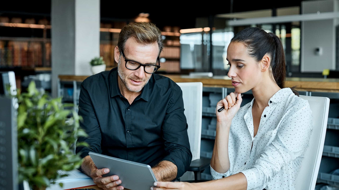 Two business colleagues review a project on a 5G-connected laptop at the office.