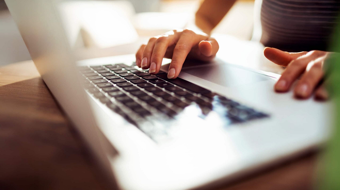 A close up of hands typing on a laptop.