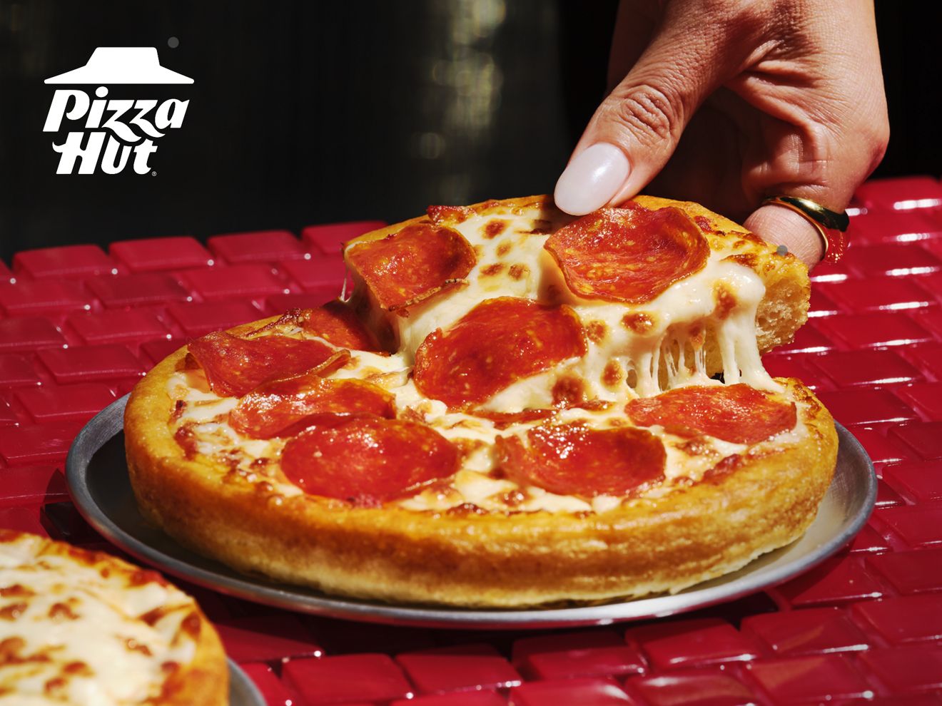 A hand is taking a slice from a Personal Pan Pizza