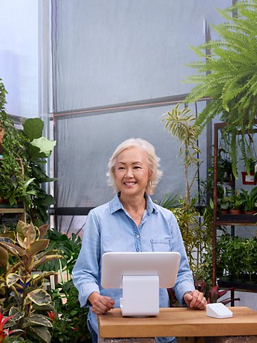 Senior lady working behind a cashier desk on a botanical store.