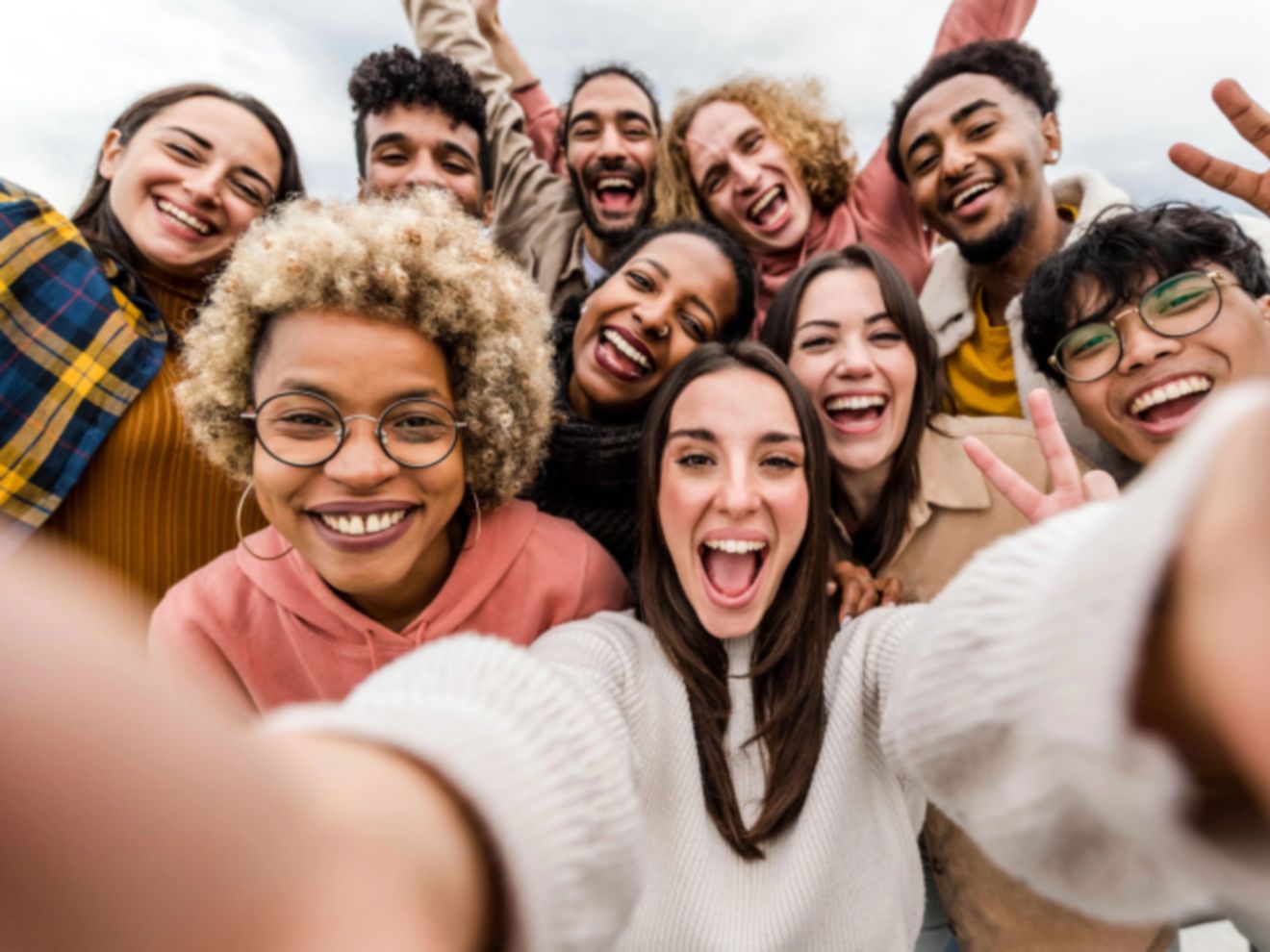 Large group of people taking a selfie with a smartphone.