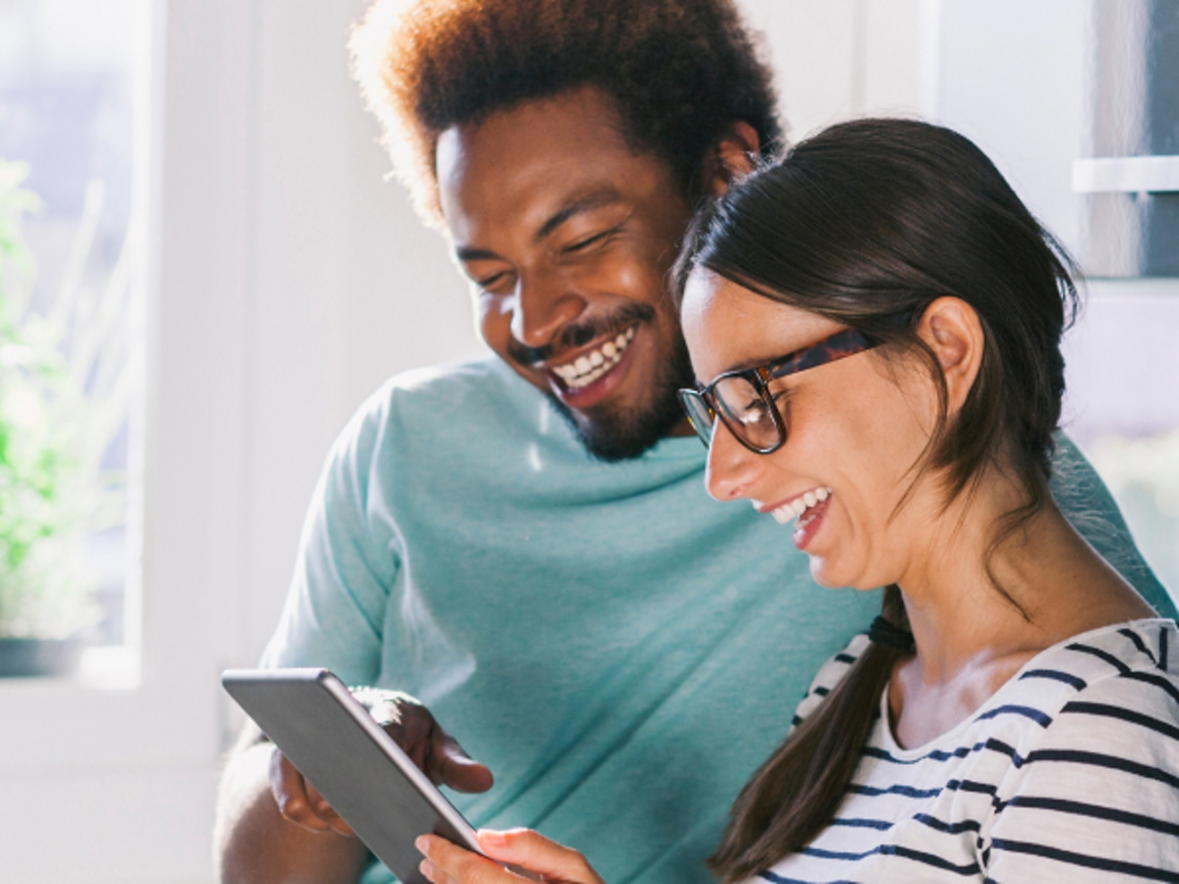 A man and woman look at a tablet together.