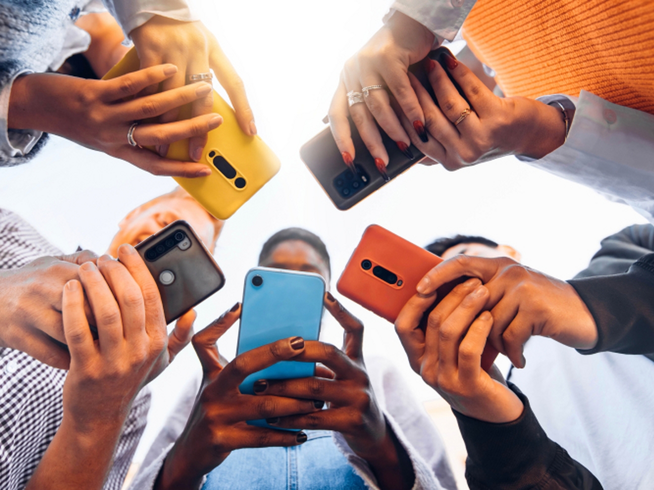 A circle of five people using their phones.