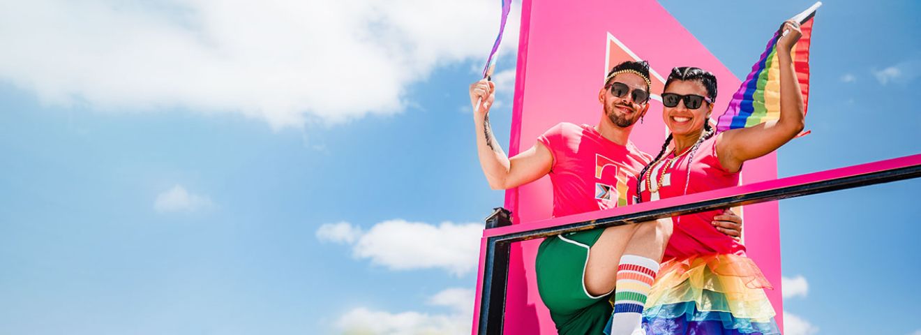 Dos personas celebrando el Orgullo en una carroza en Miami.