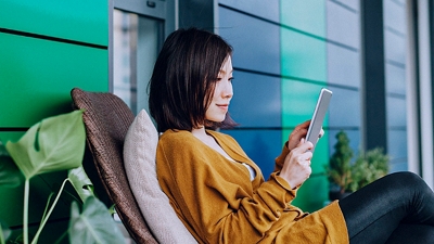 Woman relaxes on porch with her tablet.