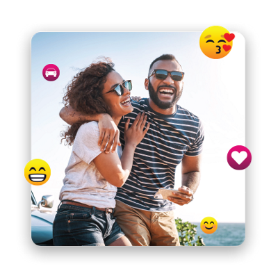 Couple in sunglasses laughing as they sit on the hood of their car.