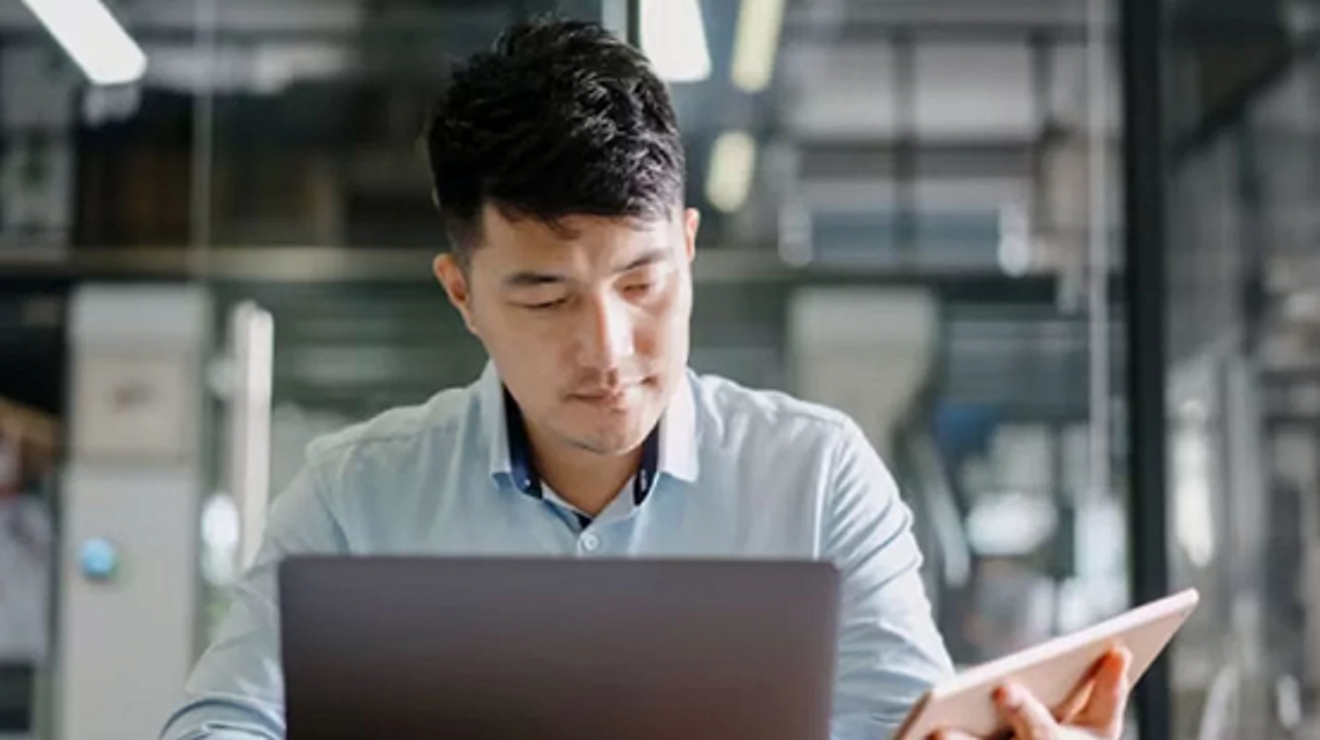 person at desk using tablet and laptop