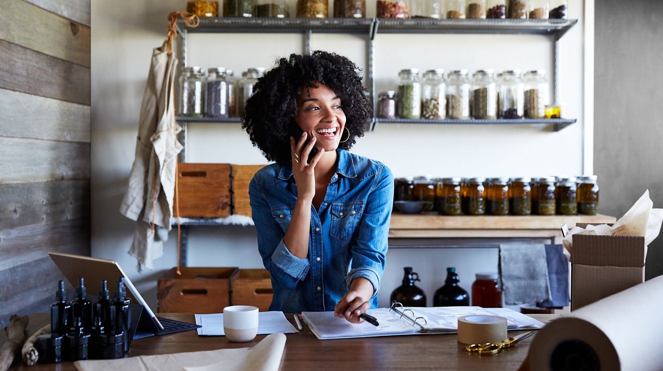 Woman siting at desk talking on her cell phone 
