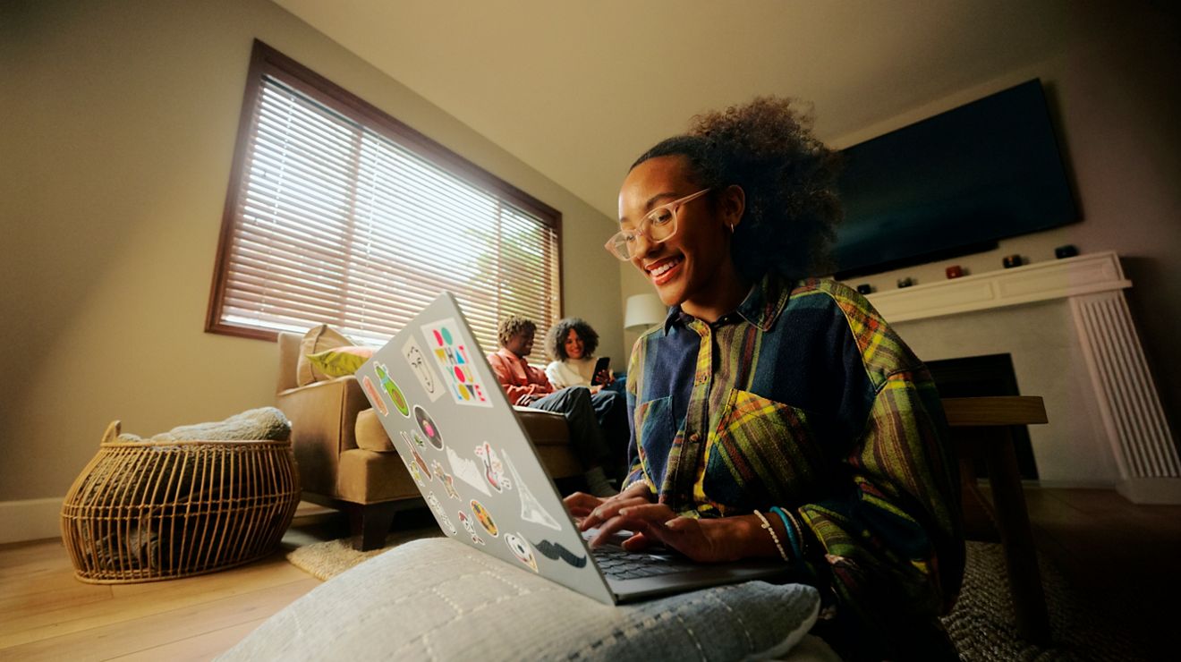 A student works on a laptop in a dorm room.