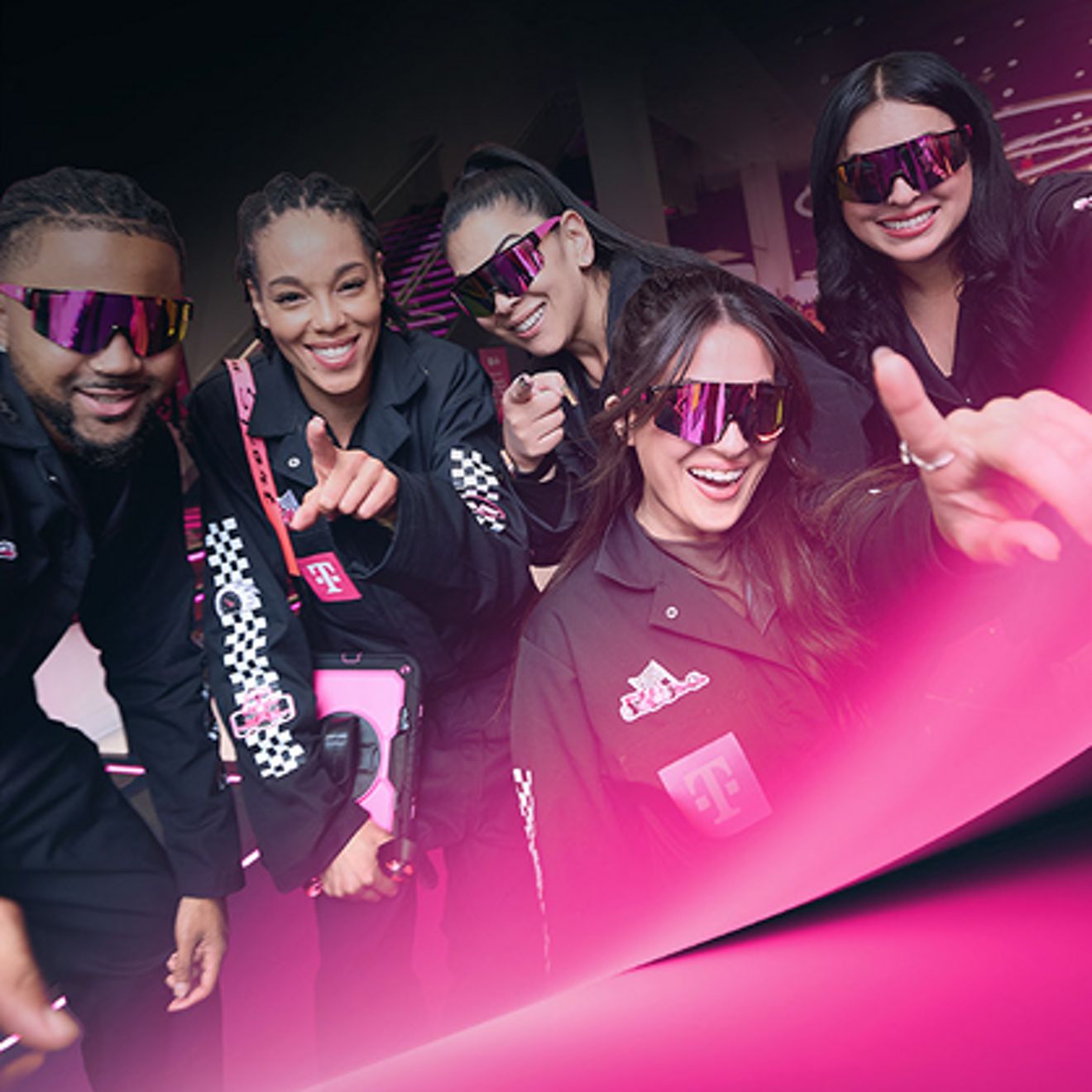 Group of F1 fans in T Mobile racing apparel enthusiastically posing for a selfie.