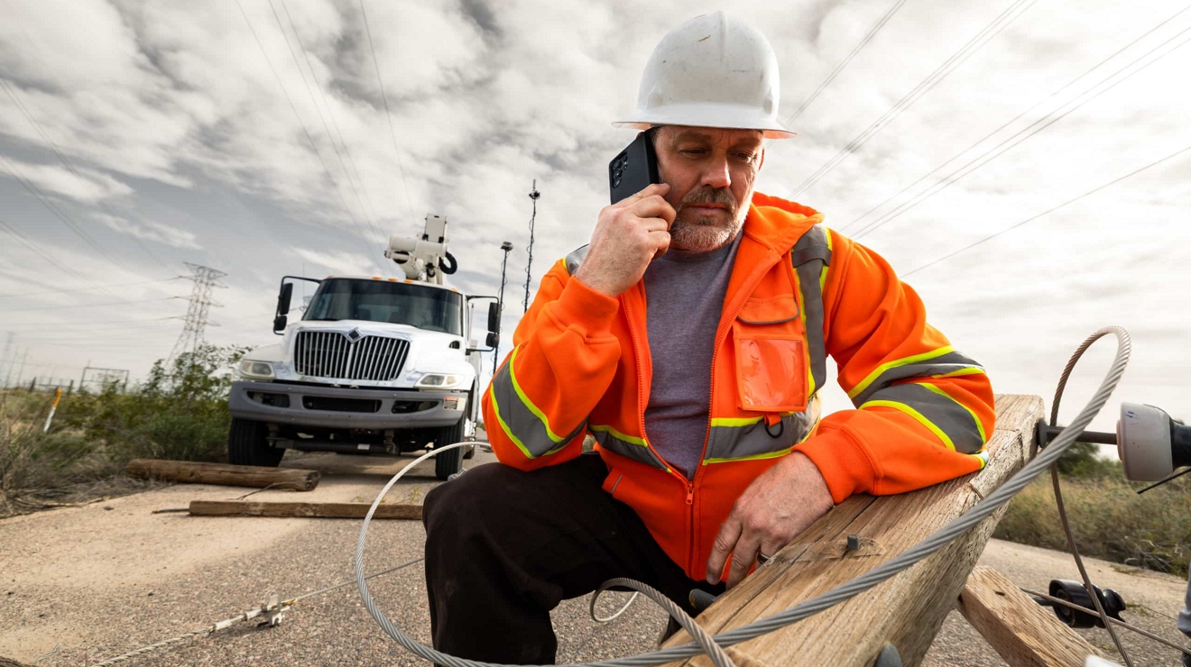 A federal first responder inspects a fallen light post while using a mobile device.