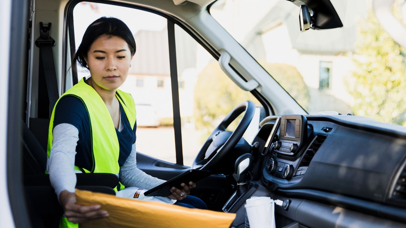 Delivery driver uses a tablet to scan a package inside a delivery van.