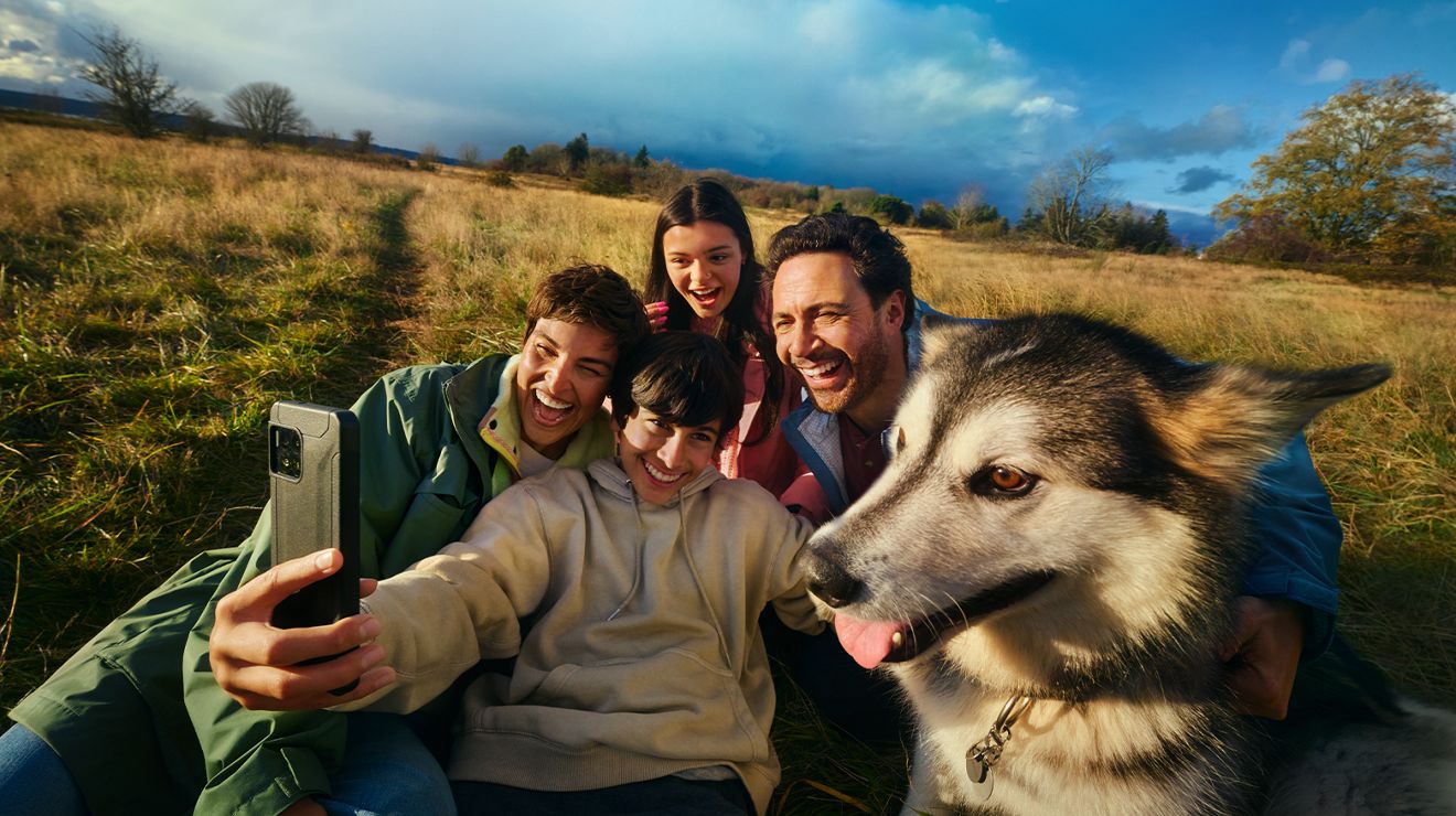 Four people take a selfie on their phone. 