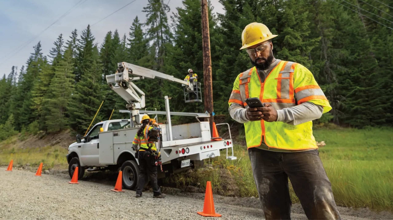 A utilities field worker uses a smartphone to report back on project status.