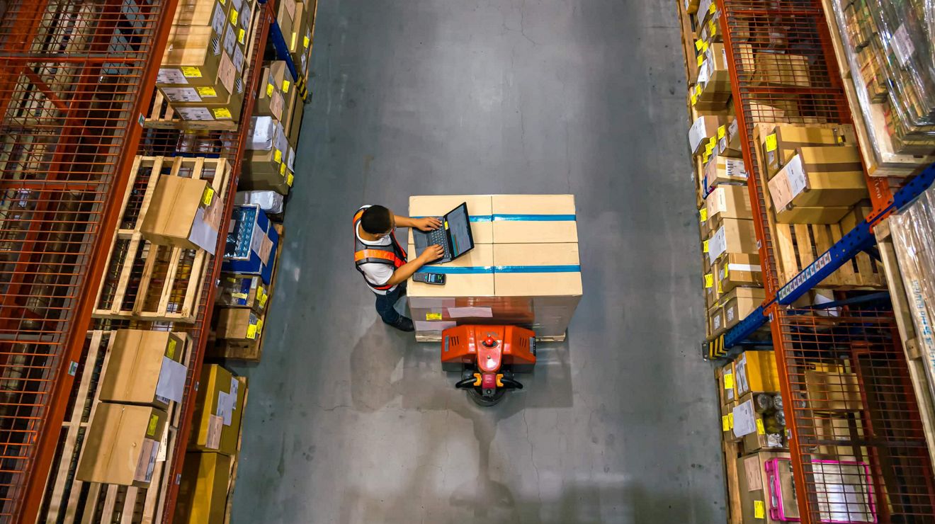 A warehouse worker uses a T-Mobile connected laptop from the crowded warehouse floor. 