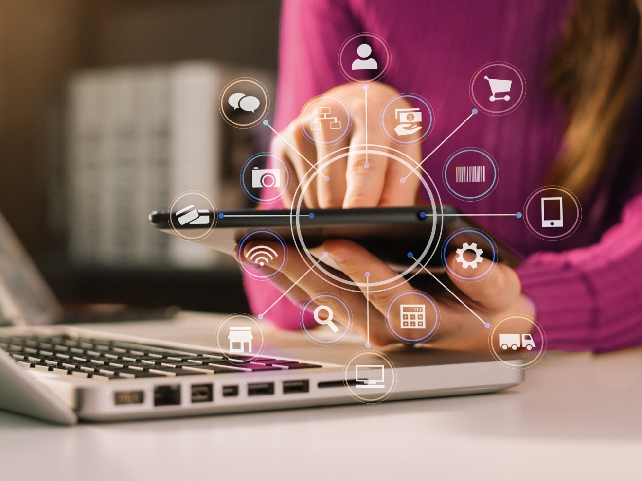 A person holds a cell phone next to a laptop. The phone screen projects a 3D display of app functions.