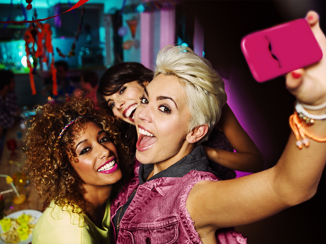 Three women are smiling as they take a selfie together.